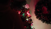 Man Decorating Christmas Tree With More Cute Ornaments At Home. - Selective Focus