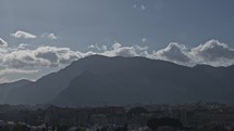 Timelapse of cloudscape and city at the bottom of mountains