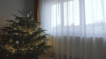 Lighted Christmas Tree Decor Next To Window With Curtain Through Sunset. Timelapse