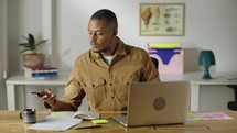 Young male professional using computer sitting at home office desk. 
