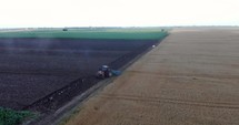 Aerial drone shot of Farmer Tilling Soil At a Farm Field With Agricultural Tractor. 
