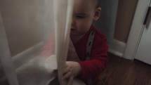 toddler boy playing in curtains 