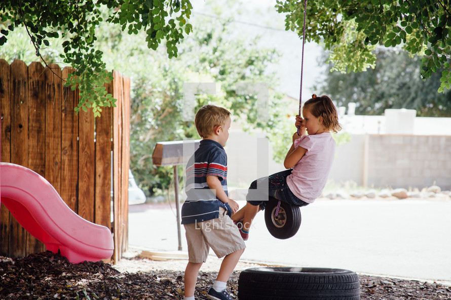 children swinging on a tire swing outdoors 