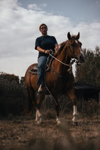 Horse riding woman on a brown stallion, western style saddle horseback rider