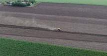 Aerial drone shot of Farmer Tilling Soil At a Farm Field With Agricultural Tractor. 