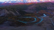 aerial view of winding river and snow capped mountains in russia at sunset 4K