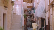 A woman walking a bicycle in the streets of Italy