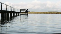 a man reading a Bible on a jetty 