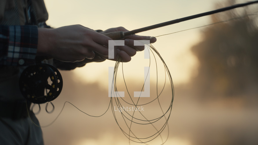 Young fly fisherman casting on a foggy river at sunrise