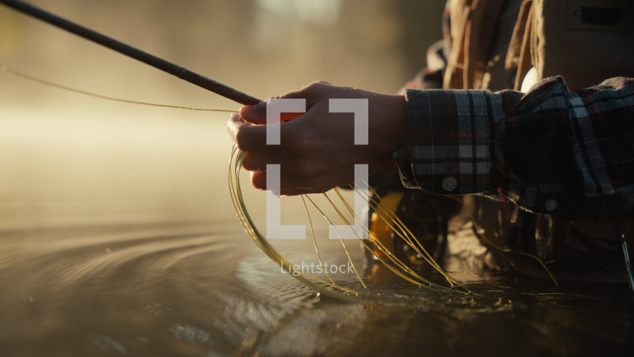 Young fly fisherman casting on a foggy river at sunrise