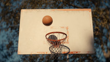 Close up of a basketball being shot on an outdoor basketball court on a sunny day