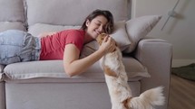 Portrait of a Woman laying on a Couch, Petting her Dog and Spending Time Bonding with Him. 

