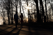 couple walking holding hands down a dirt road 