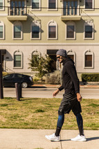 A man in workout gear walking down a sidewalk.