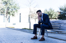 man in a suit sitting on a bench in prayer