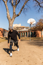 A man exercising outdoors near a basketball goal.