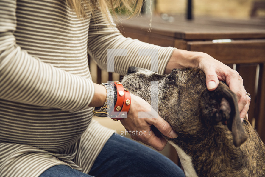 a pregnant woman petting her dog 