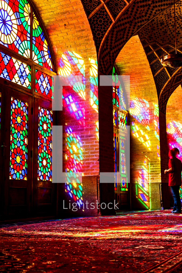 colors from stained glass windows shining on a rug in a mosque 