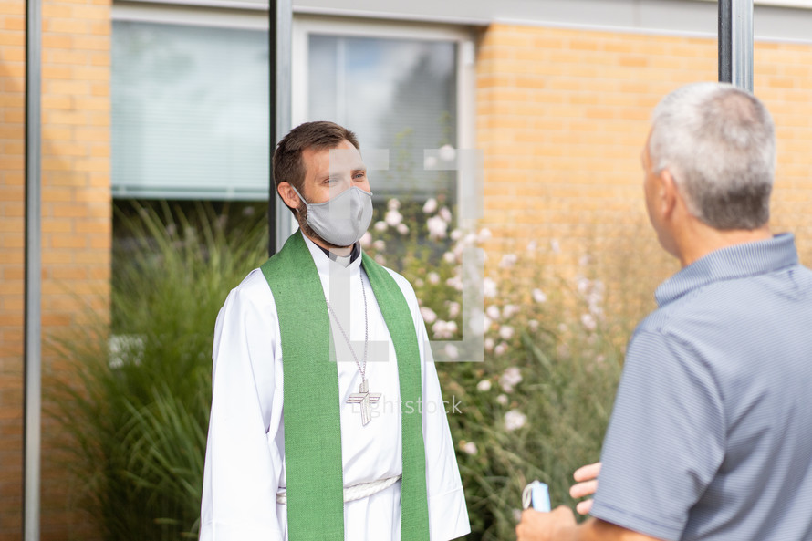 Lutheran pastor in a mask greeting parishioners 