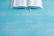 open Bible on a blue wood background 