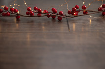 red berries and fairy lights on a wood background 