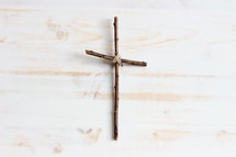simple cross of sticks on a white wood background 