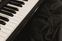Black and white - piano keyboard with blanket on the bench