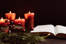 Christmas garland with berries and candles and open Bible