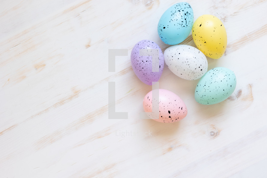 speckled Easter eggs on white wood background 