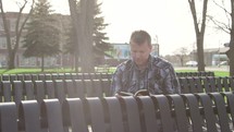 a man reading a Bible on a bench 