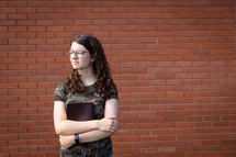 a teen girl holding a Bible standing in front of a brick wall 