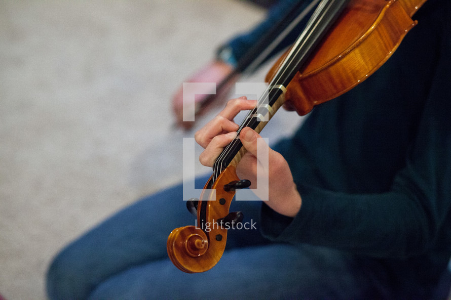 A seated musician playing a violin.