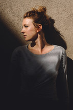 young woman standing in shadows looking to the side 