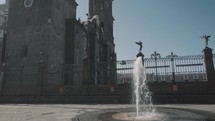 Slow-motion of small fountain in front of historic Puebla Cathedral during summer day,Mexico - close up tilt up