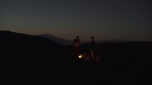 standing by a campfire on a mountaintop at night 