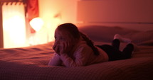 child watching tv on a bed 