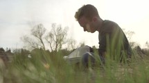 a man sitting in the grass reading a Bible 