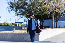 man in a sports coat and sunglasses walking in a city 