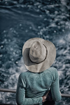 woman in a hat looking over the railing on a boat 