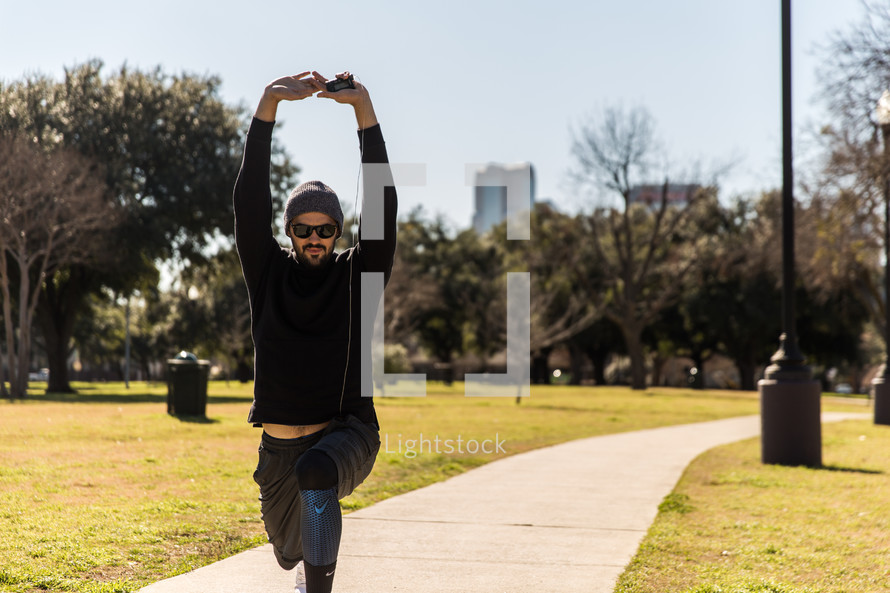 A man in workout clothes exercises in a park.