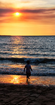 boy running on a beach at sunset 