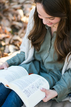 a woman reading from a Bible in her lap 