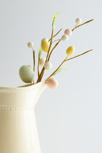 Decoration sprig with easter eggs in a yellow pitcher with copy space