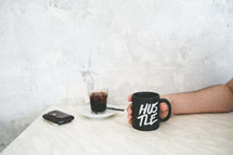 a man holding a coffee mug with the words hustle 