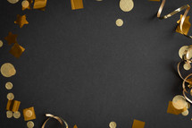 Gold streamers and confetti on a black background with copy space