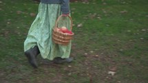 a woman in a long skirt picking apples in an orchard 