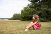 young girl sitting outdoors 