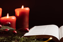 Christmas garland with berries, candles, and open Bible