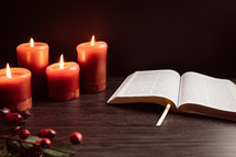 Christmas berries and candles with open Bible
