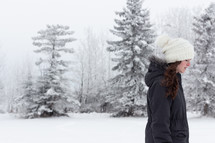 a teen girl standing outdoors in winter in a coat and wool cap 